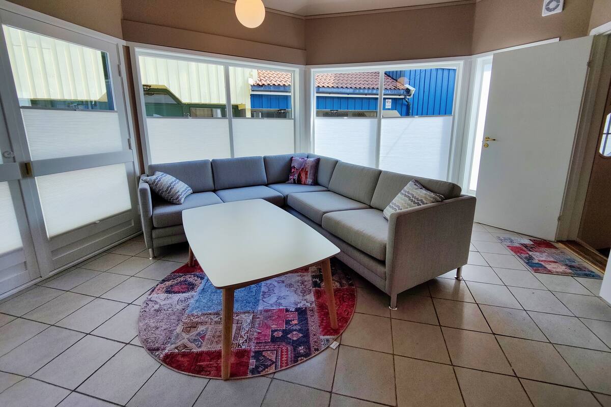 A living room with a grey sectional sofa, a white coffee table, and a colorful rug.