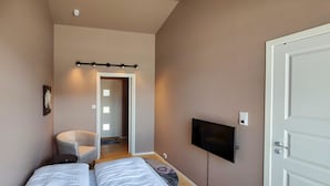Een slaapkamer met twee bedden, een televisie en een stoel.