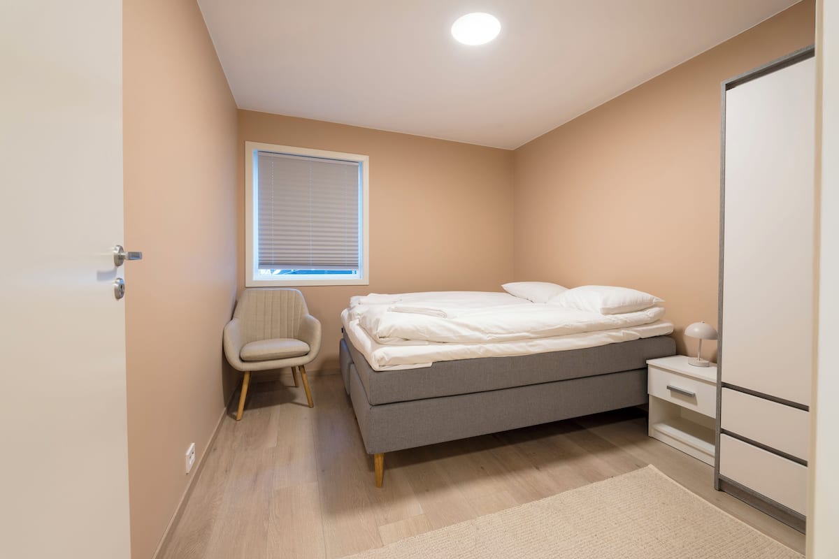 A bedroom with a bed, bedside table, chair, and wardrobe.