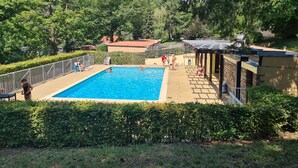 A rectangular swimming pool surrounded by a fenced area with a covered seating area and a small building. - Appartement au Calme Dans Residence Avec Piscine, Entouré de Foret (Bœrsch)