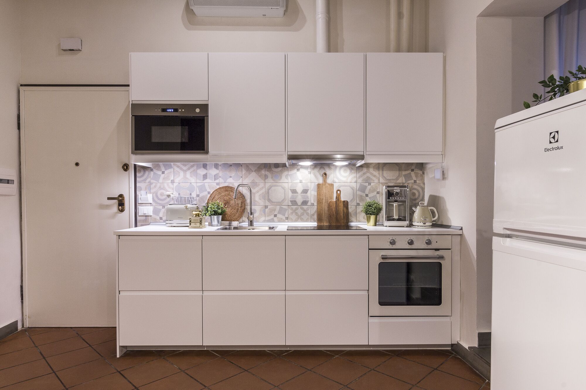A modern kitchen with white cabinets, a microwave, a stove, and a refrigerator.