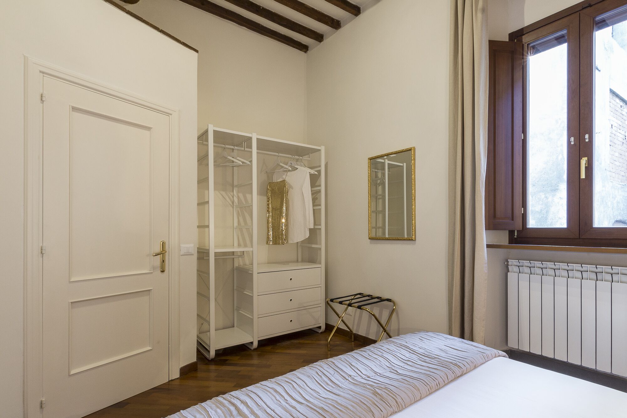 A bedroom with a bed, a wardrobe, a radiator, and a window.