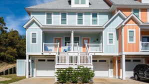 A two-story residential building with a front porch, a garage, and a small balcony.