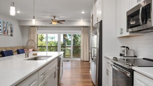 A modern kitchen with white cabinetry, stainless steel appliances, and a wooden floor.