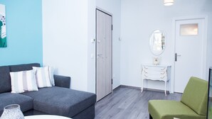 A modern living room with a grey sofa, a green armchair, a white coffee table, and a small white dresser with a mirror. - Chic apartment in Athens (Athens)