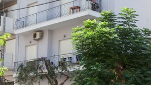 A multi-story residential building with balconies, a tree in front, and parked cars. - Chic apartment in Athens (Athens)