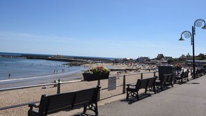 A seaside promenade with benches and a signboard. - Bell Cliff House (Lyme Regis)