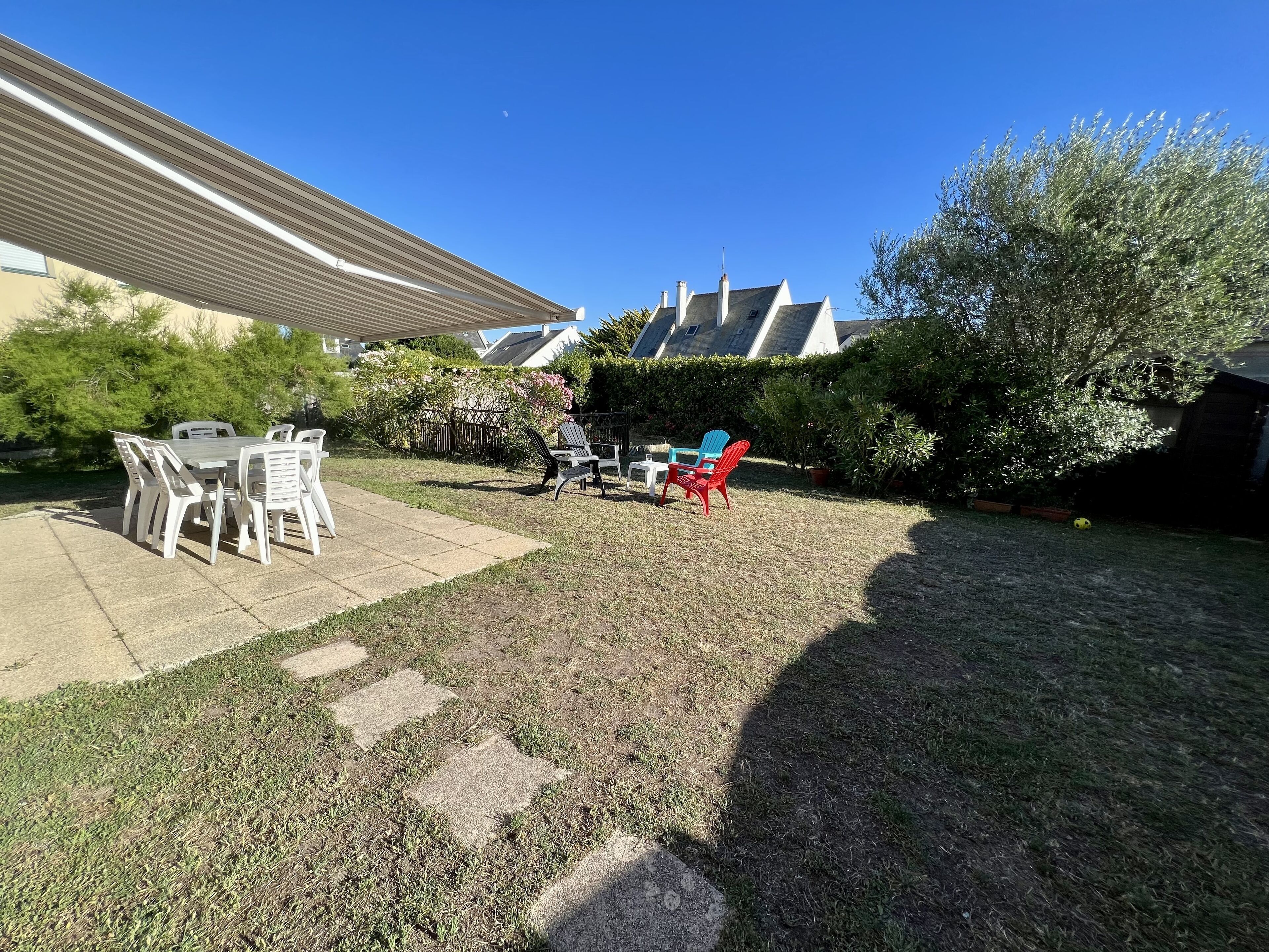 Un jardin avec un espace patio, du mobilier d’extérieur et une pelouse.
