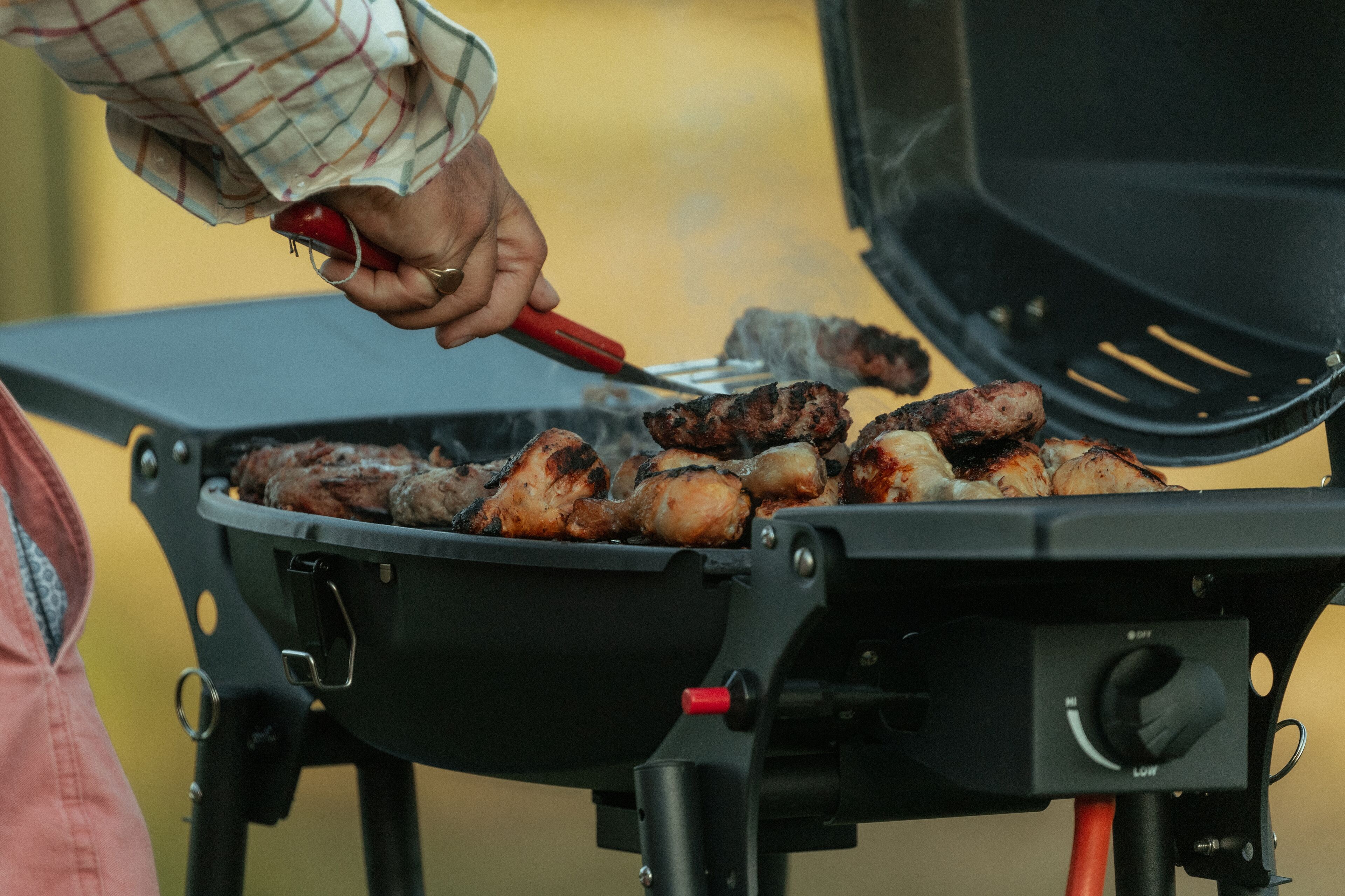 Una persona asando carne en una parrilla al aire libre.
