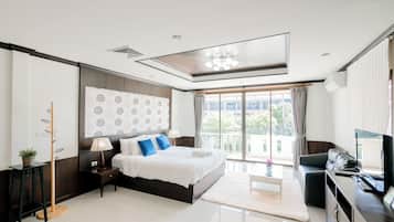 A modern bedroom with a large bed, a desk, a chair, a TV, and a balcony with curtains.