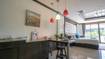 Una cocina moderna con armarios oscuros, encimera de granito y zona de comedor con mesa y sillas. Hay un cuadro en la pared y un ventanal con vistas al exterior.