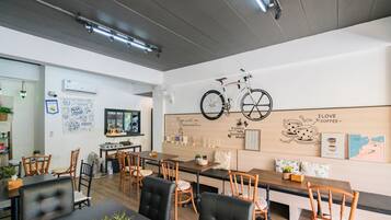 A modern cafe with wooden furniture, a bicycle mounted on the wall, and various wall decorations.