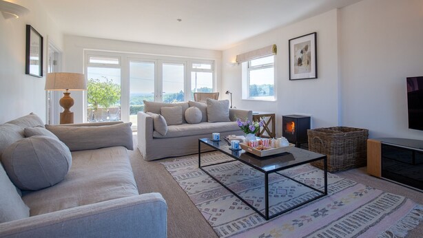A modern living room with a sofa, a coffee table, a fireplace, and a TV. - Ridgeway Farmhouse at Ragley Estate, Alcester - sleeps 8 guests  in 4 bedrooms (Alcester)
