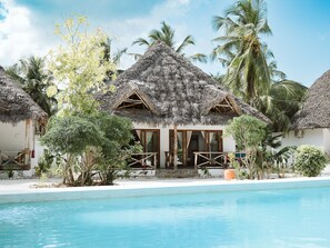 A resort with thatched-roof cottages, a swimming pool, and tropical vegetation. - JOY OF ZANZIBAR (Michamvi)
