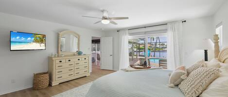 Un dormitorio con cama, cómoda, televisor y vista a una piscina y zona exterior.