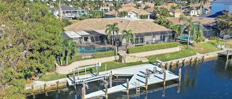 A residential property with a large house, a swimming pool, and a dock extending into a body of water.