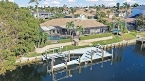 A residential property with a large house, a swimming pool, and a dock extending into a body of water. - Direct Boating Access Home | Pool/Spa & Billiards (Marco Island)
