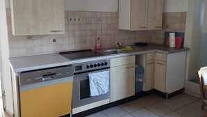Een keuken met een vaatwasser, oven, spoelbak en kastjes.
