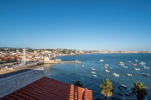 Une ville côtière dotée d’une tour imposante, d’un port de plaisance avec des bateaux et d’un ciel d’un bleu éclatant.