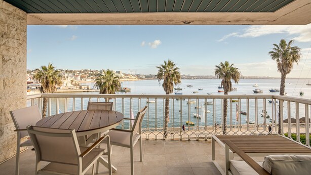 A balcony with a view of the sea, a wooden table, and chairs. - Apartment 'Cascais Bay Terrace IV' with Sea View & Wi-Fi (Cascais)