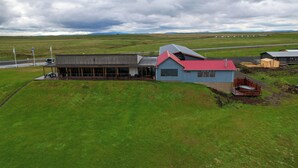 A building with a red roof and a large open area in front. - West Ranga lodge (Rangárþing ytra)
