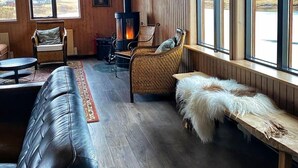 A cozy living room with a fireplace, leather sofa, and a bench with fur. - West Ranga lodge (Rangárþing ytra)