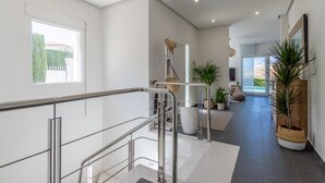Et moderne interiør med trappe, udsigt udad og et siddeområde med planter.