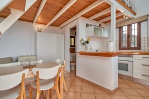 Une cuisine moderne avec des armoires blanches, une table à manger en bois et un revêtement mural en carreaux.