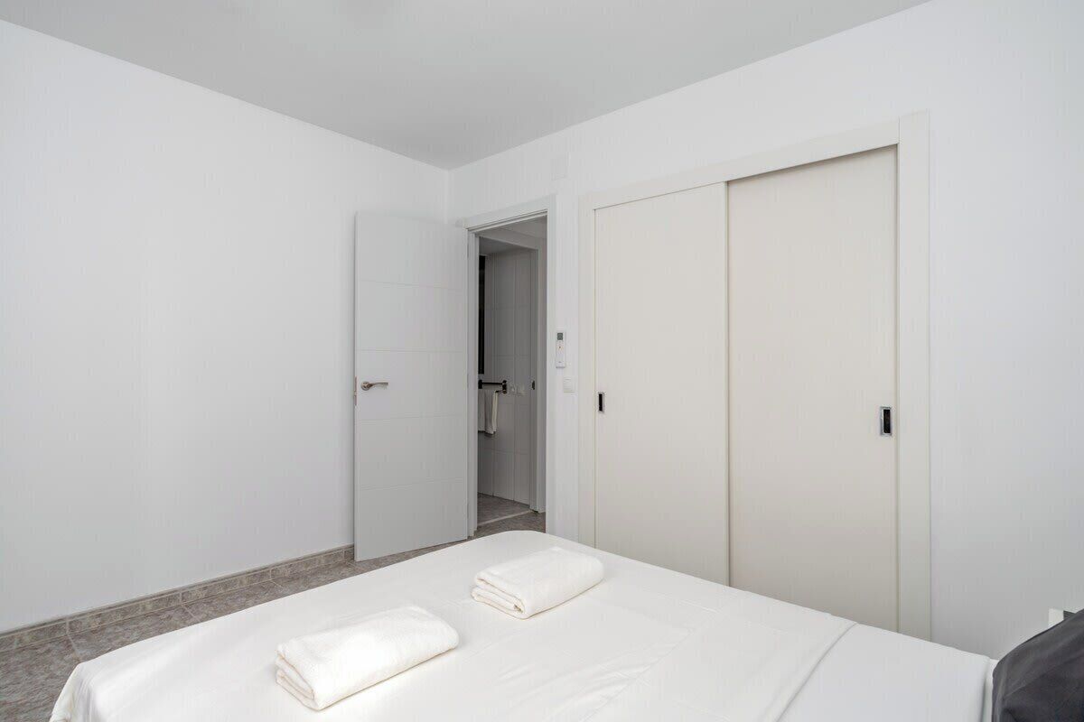 Habitación de hotel con cama, dos toallas, armario y puerta que da a un baño.