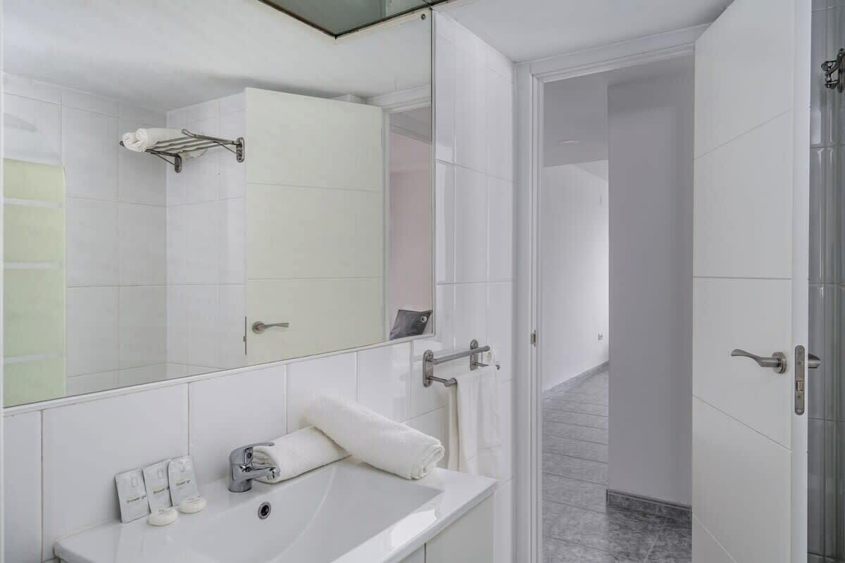 A modern bathroom with a white sink, mirror, and towel rack.