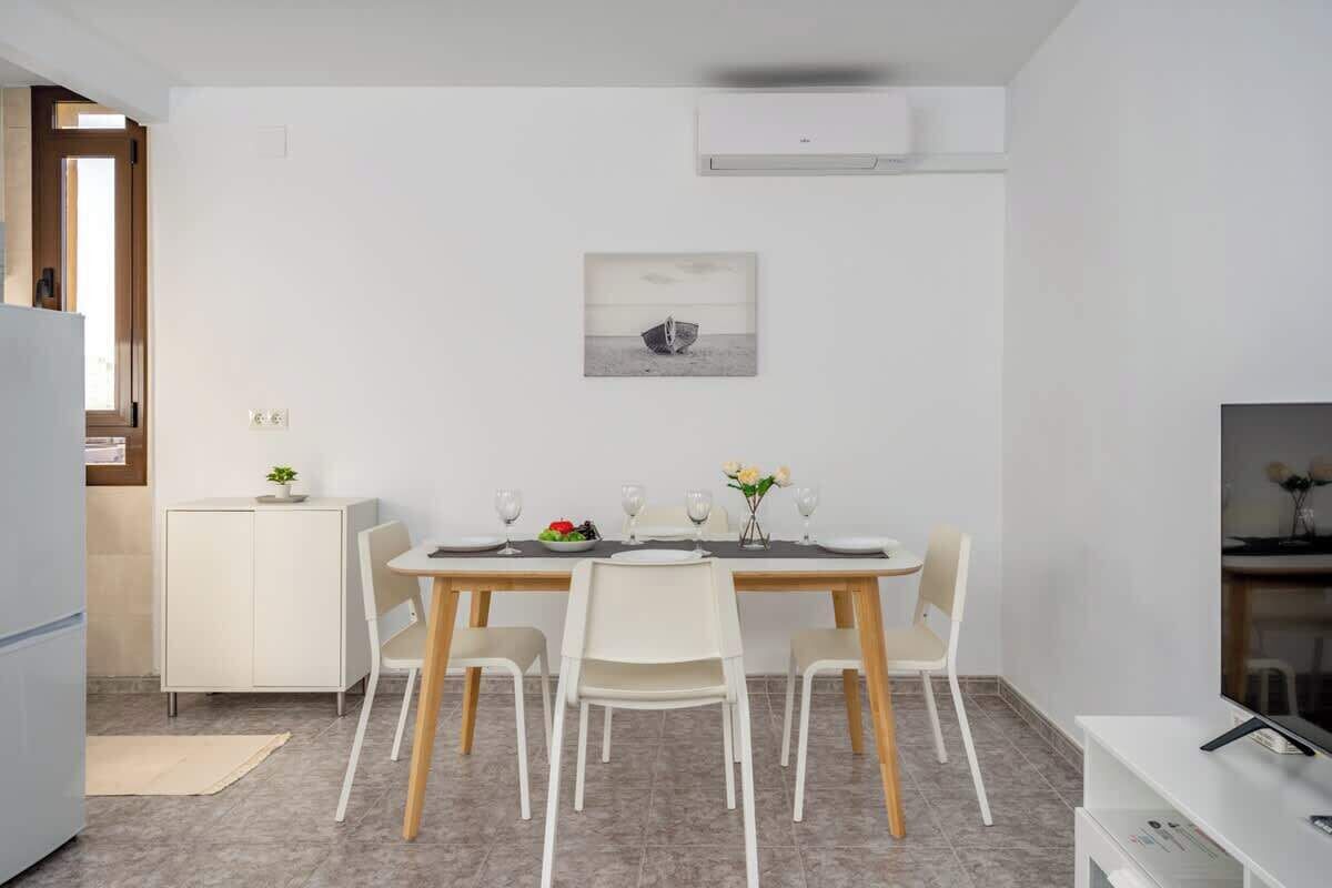 A modern dining area with a wooden table and four chairs, a white cabinet, and a small plant on the cabinet.