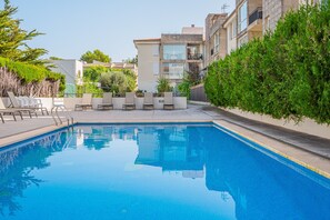 A swimming pool with a tiled edge, surrounded by lounge chairs and a low wall with greenery. - Holiday Apartment Llenaire cerca playa with Mountain View, Shared Pool & Wi-Fi (Port de Pollença)