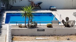 Una piscina con un cactus y una planta de palma, una silla de descanso y un cartel con un número.