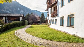 Un sentiero lastricato che conduce a un edificio con facciata bianca e balconi in legno.