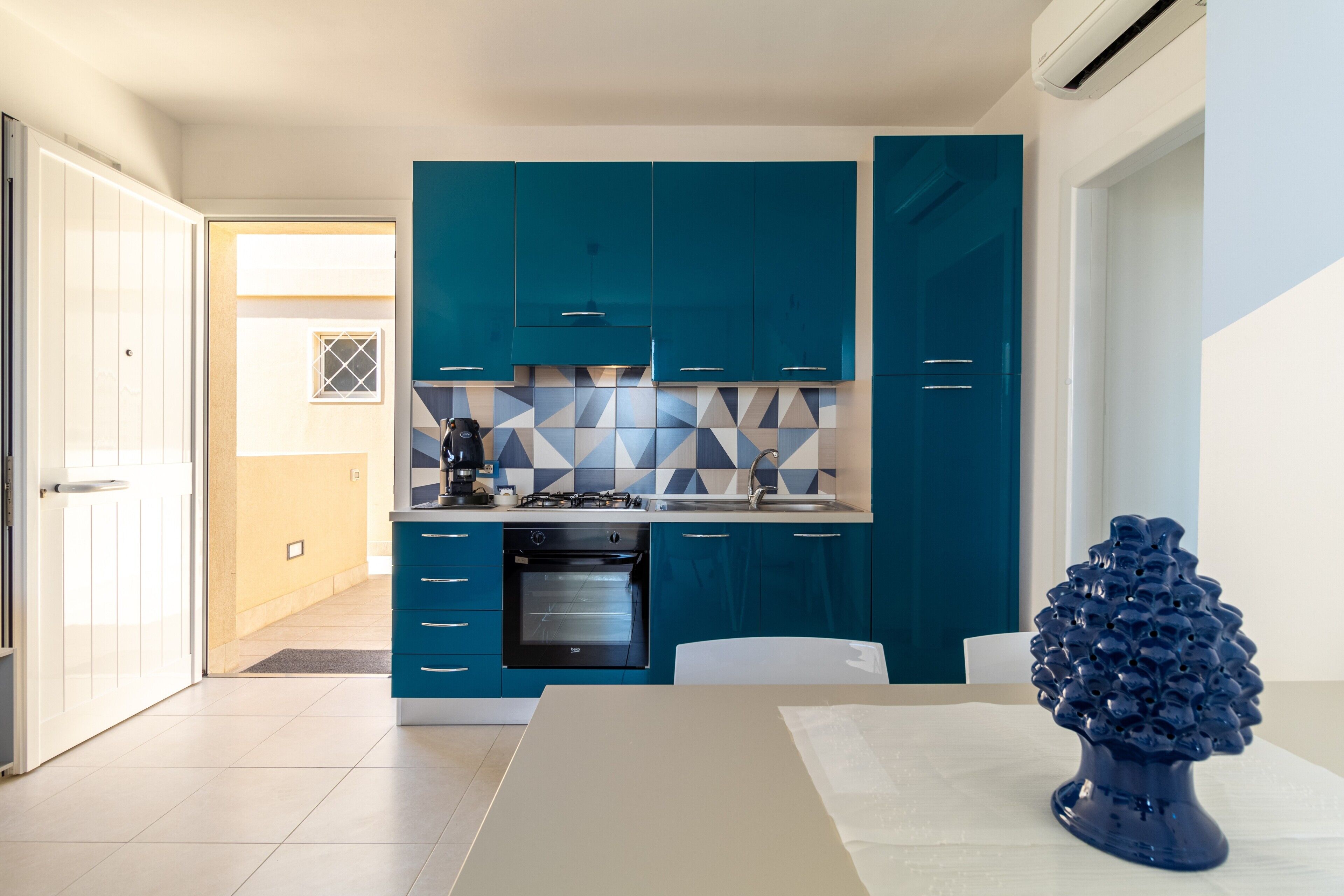 Une cuisine moderne avec des armoires de couleur turquoise, une cuisinière à gaz et un four à micro-ondes.