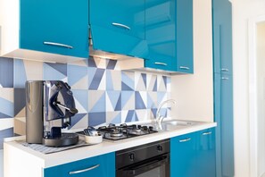Una cucina moderna con mobili blu, una macchina da caffè, un piano cottura e un lavello.
