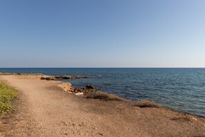 Un sentiero costiero con affioramenti rocciosi e mare calmo.