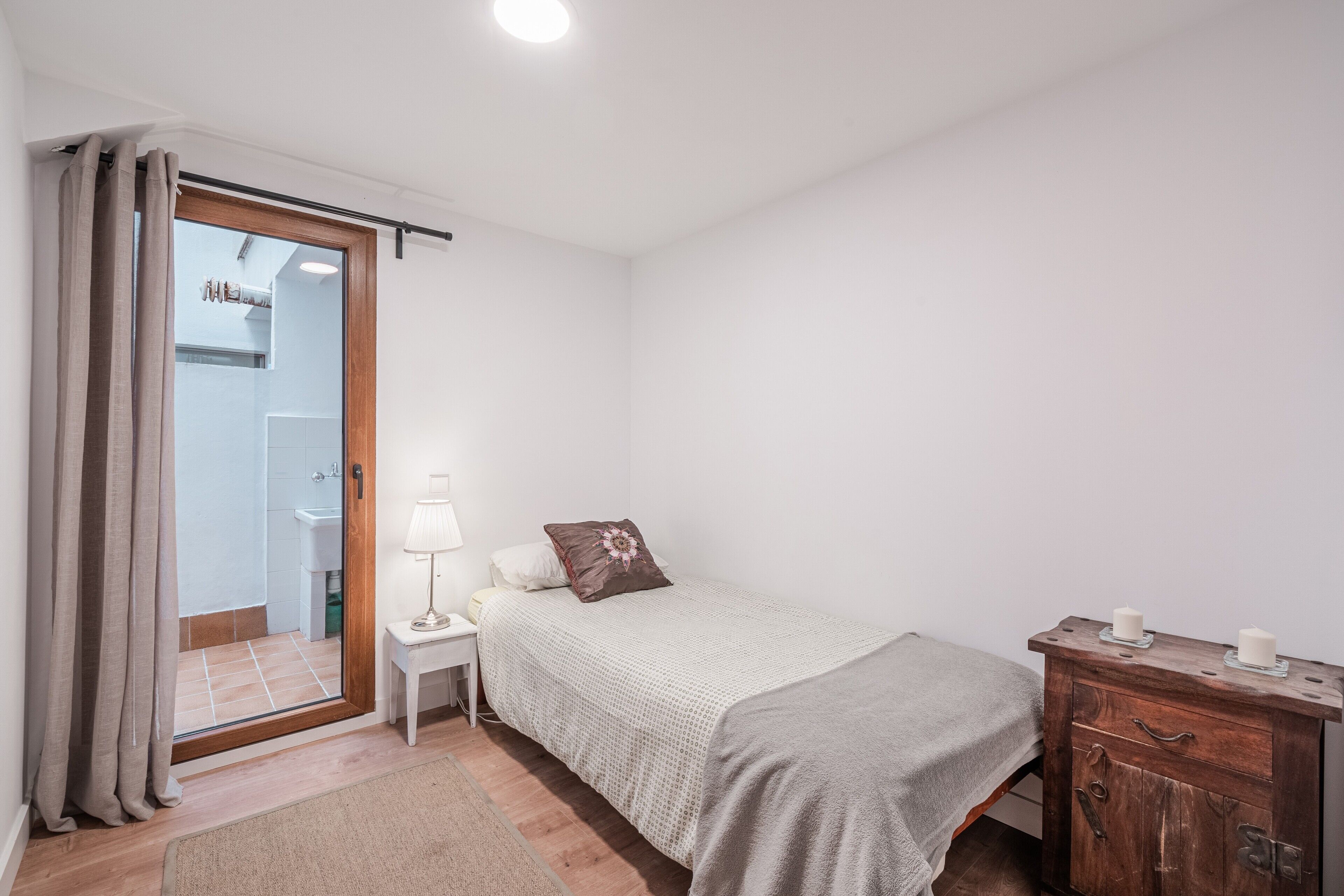 Ein Schlafzimmer mit Bett, Nachttisch, Kommode, einer Tür zu einem Badezimmer und einem Fenster.