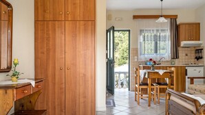 Eine Küche mit Holzausstattung, einem Esstisch mit Stühlen und einem Fenster mit Vorhängen.