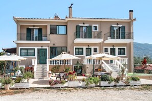 A two-story building with a balcony, outdoor seating, and potted plants. - Studio Apartment Daratos studio 2 with Sea View, Shared Garden & Wi-Fi (KEFALONIA)