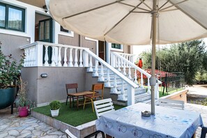 A patio with a table, chairs, and an umbrella. - Studio Apartment Daratos studio 2 with Sea View, Shared Garden & Wi-Fi (KEFALONIA)