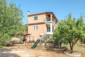 A multi-story building with a balcony, a slide, and outdoor seating.