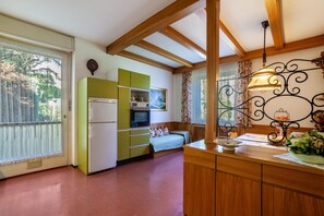 A compact kitchen with a refrigerator, microwave, and green cabinets.