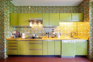A kitchen with green cabinets, a yellow countertop, and patterned tile walls.
