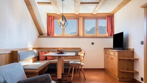 Um quarto aconchegante com um banco de madeira, uma mesa e uma televisão.
