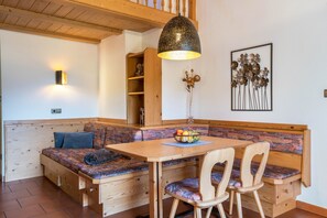 A wooden bench with a table and chairs, a wall-mounted light fixture, and a decorative wall piece. - Apartment Häuslerhof Tilia with Mountain View, Balcony & Wi-Fi (Niederdorf)