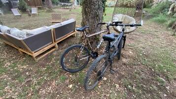 En cykel står parkerad bredvid en träbänk och ett träd på en bakgård.