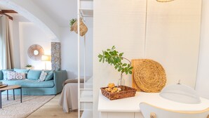 Een moderne woonkamer met een bank, salontafel en een wit bureau met een mand vol lekkernijen.