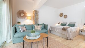 Een gezellige kamer met een bank, een bed, een ronde houten tafel en een stenen zuil.