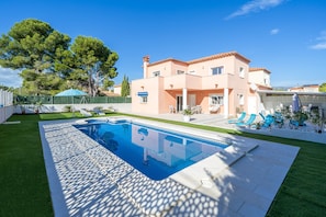 Une maison à deux étages avec une piscine, un patio couvert et un jardin clôturé.